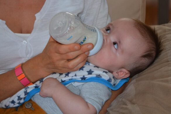 A lady is feeding a baby through a feeder