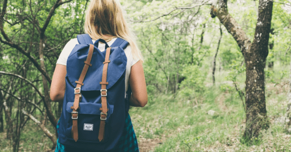A lady wearing a backpack walking in a jungle